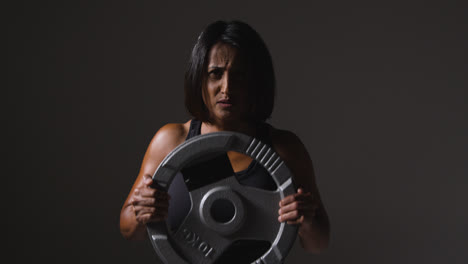 Foto-De-Estudio-De-Una-Mujer-Madura-Que-Usa-Ropa-De-Gimnasio-Levantando-Pesas-Para-Hacer-Ejercicio-Cardiovascular